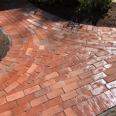 Brick pavers installed in custom patterns for walkways and patios as shown here by landscape design and construction company Nest Outdoors