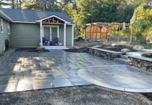 Custom landscape design with a bluestone patio in Bedford New Hampshire by Nest Outdoors